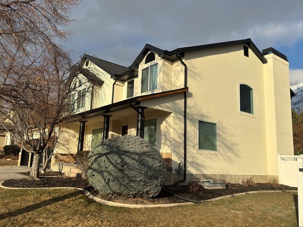 Modern two-story home with a light exterior, large windows, and landscaped yard.