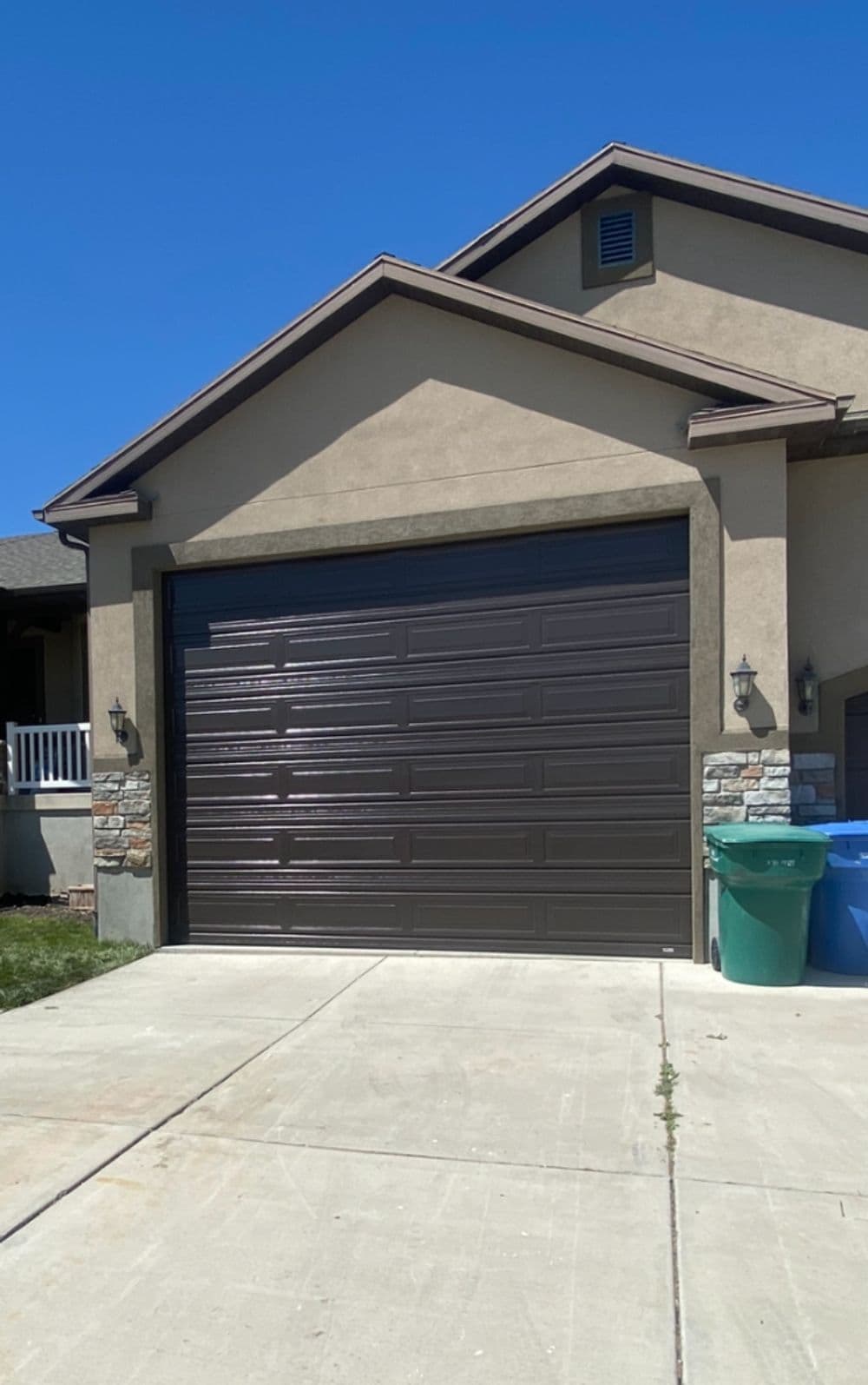 Modern home with a dark garage door, stone accents, and a tidy driveway.