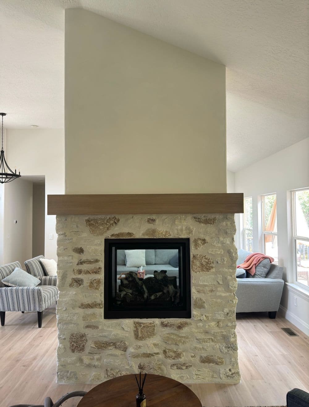 Modern living room featuring a white stone fireplace with a wooden mantel and cozy seating.