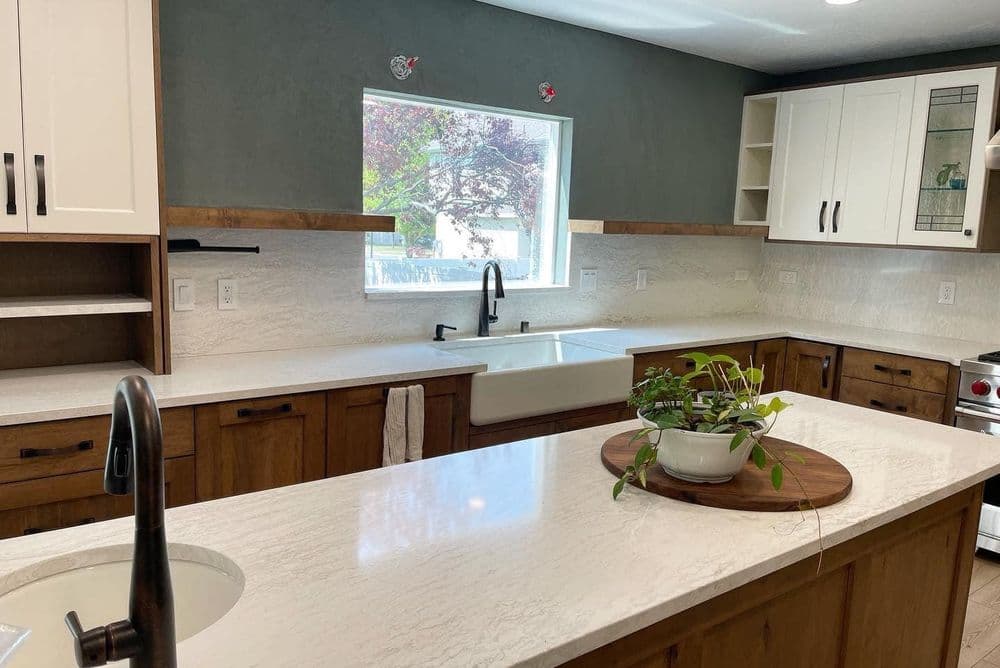Modern kitchen with white marble countertops, wooden cabinets, and a farmhouse sink.