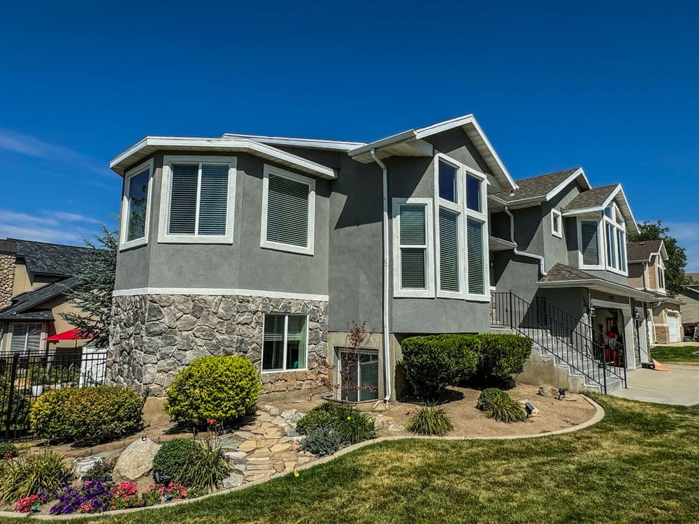 Modern gray house with stone accents, large windows, and landscaped front yard.