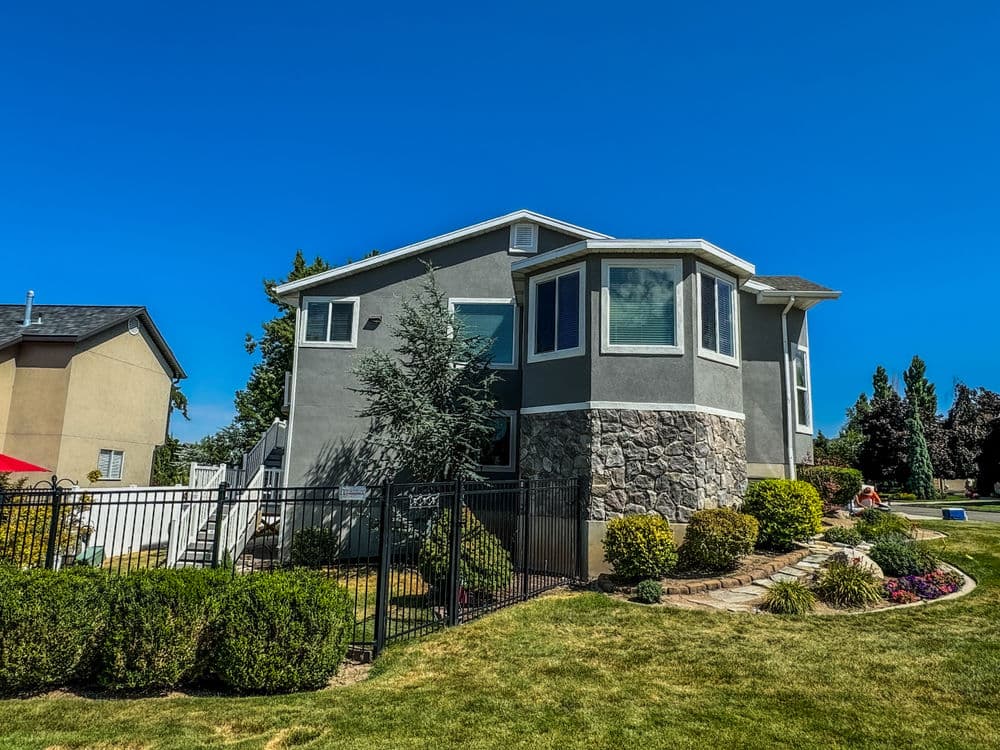 Modern two-story home with stone accents, landscaped yard, and clear blue sky.
