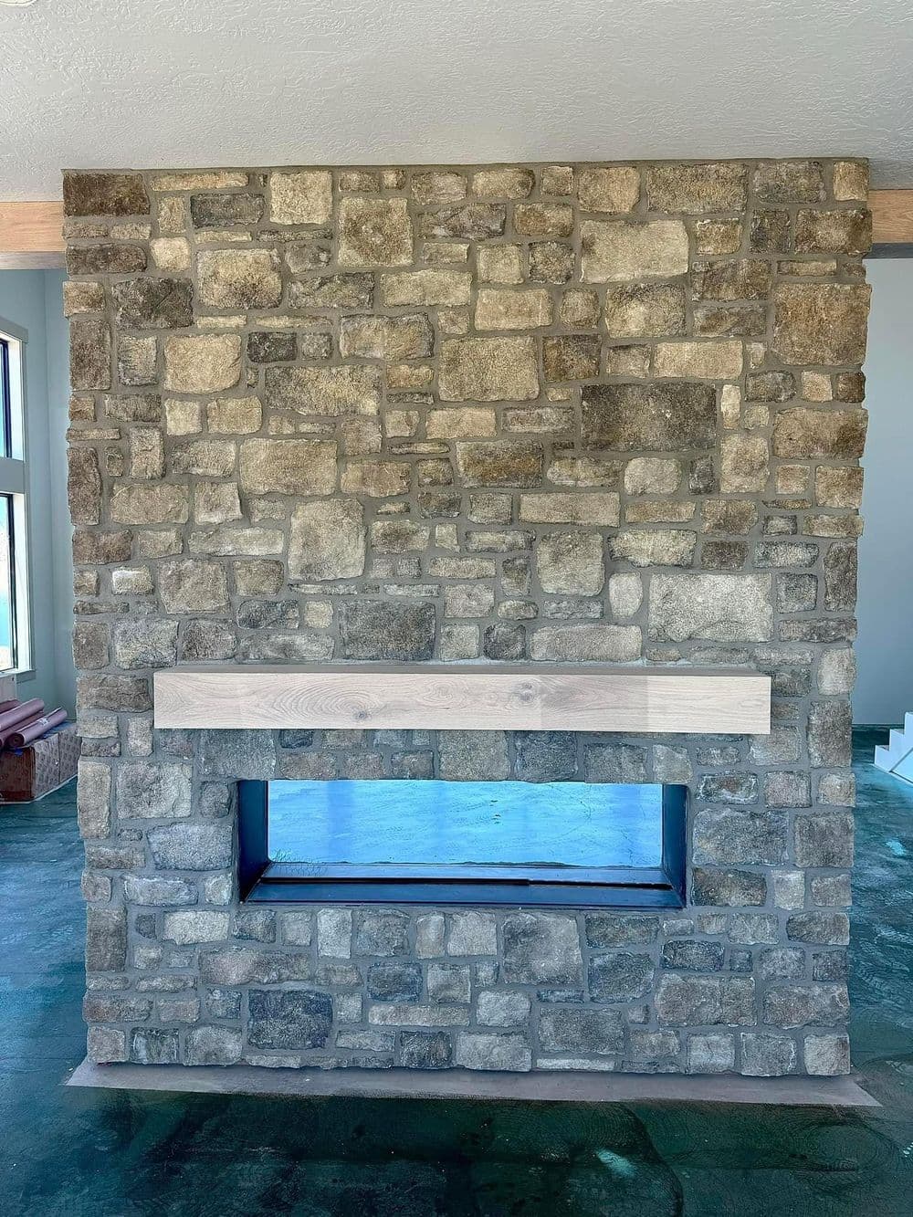 Modern stone fireplace with wooden mantel and open design, featuring stylish interior decor.