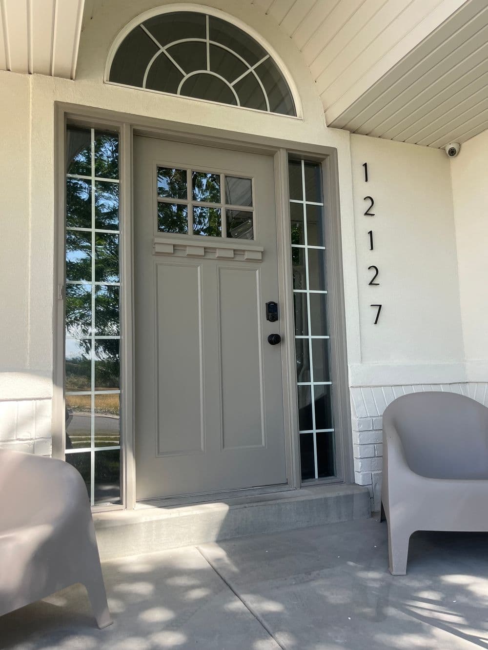 Front entrance of a modern home featuring a gray door, large windows, and house number 12127.