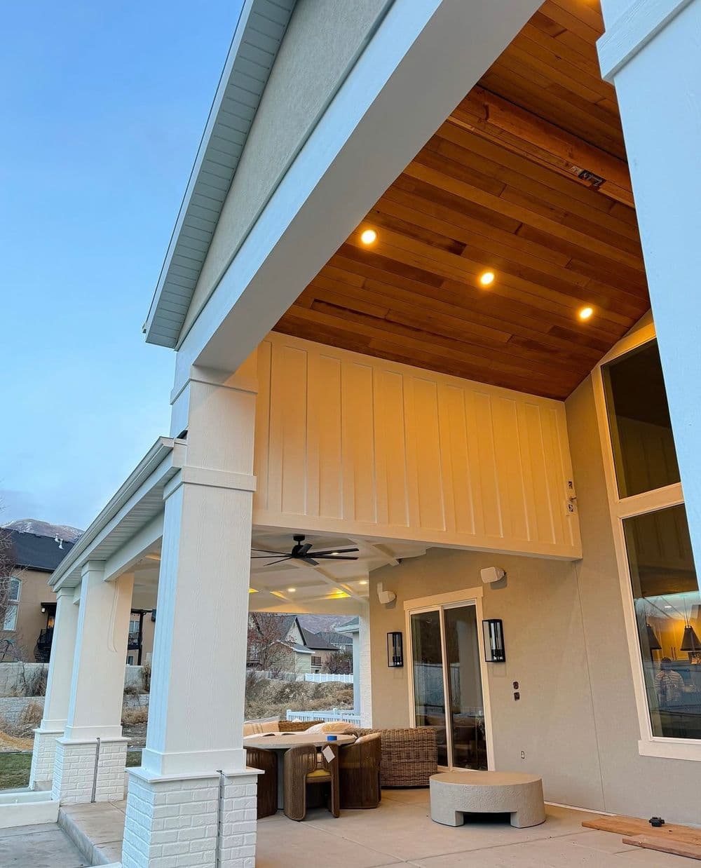 Modern outdoor patio with wooden ceiling, stylish furniture, and scenic mountain view.