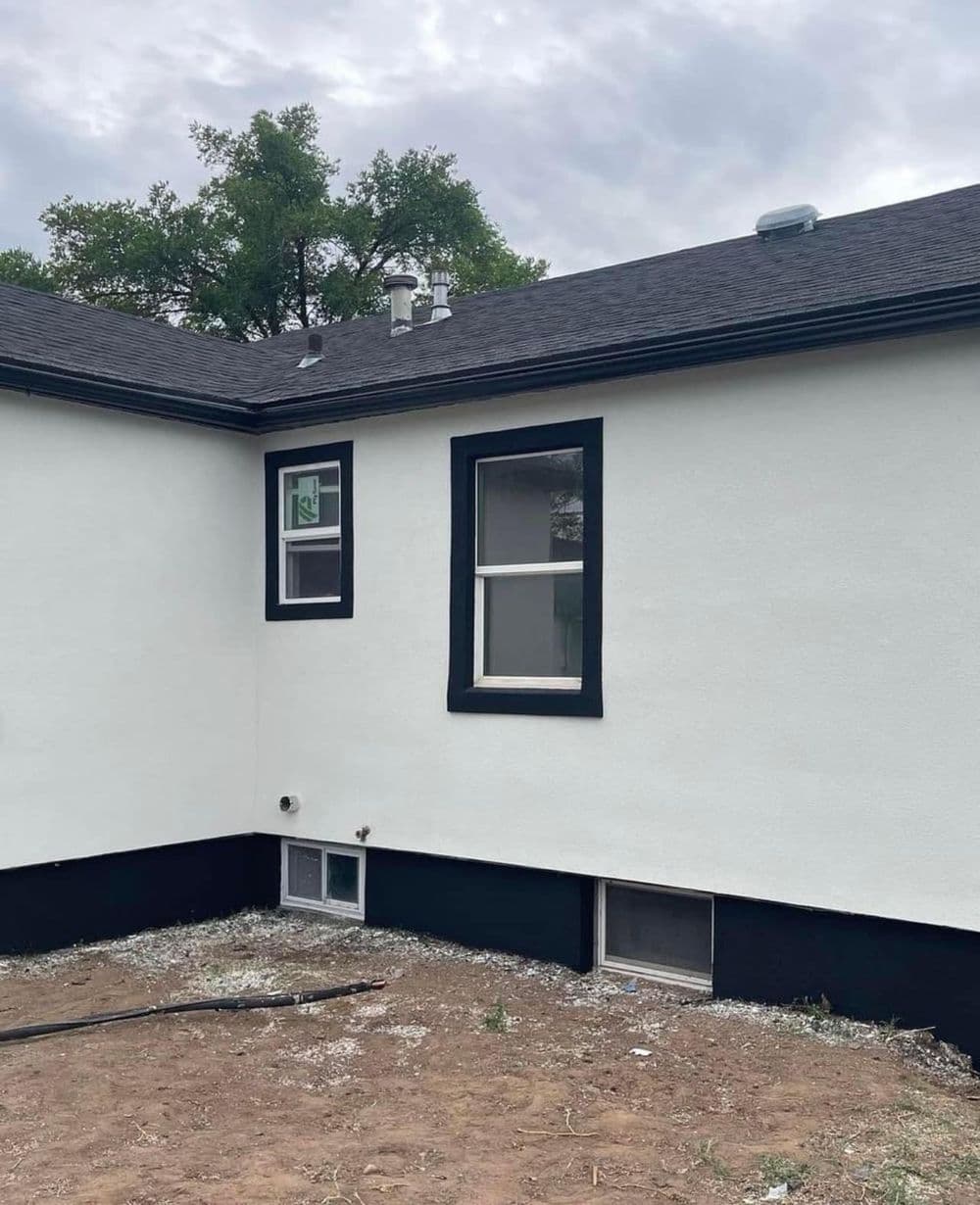 Renovated exterior of a house featuring white stucco walls and black trim.