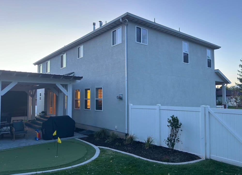 Two-story home exterior with landscaped yard and putting green, featuring a covered patio.