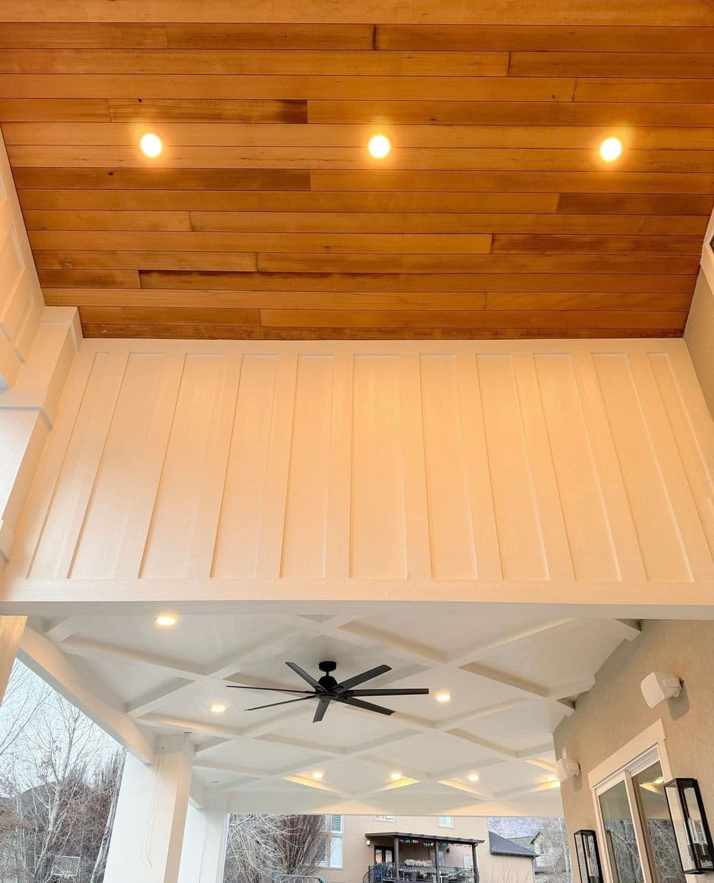 Modern covered patio showcasing wooden ceiling, recessed lighting, and ceiling fan.