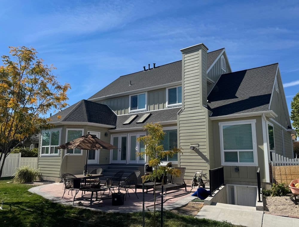 Modern two-story home with patio, outdoor seating, and beautiful landscaping on a sunny day.