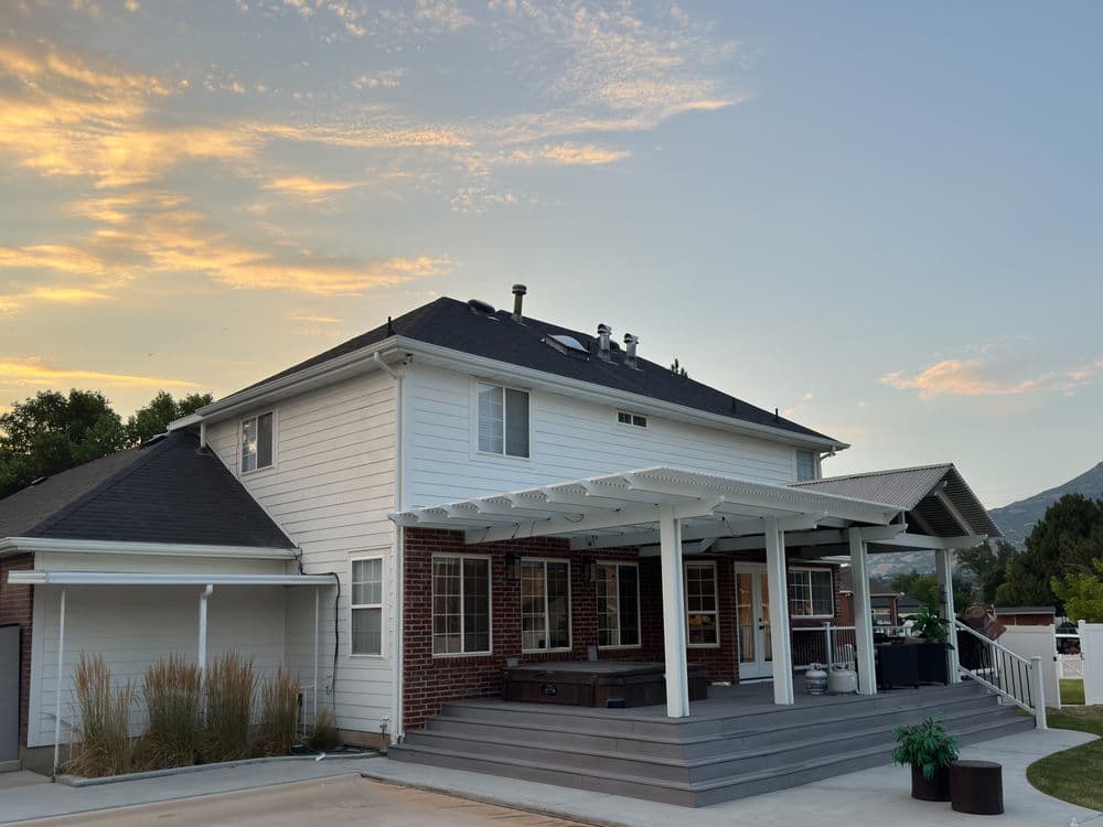 Modern two-story home with a landscaped patio and sunset sky in the background.