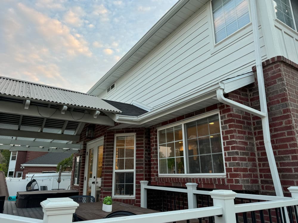 Modern home exterior featuring brick walls and spacious patio area under a corrugated roof.